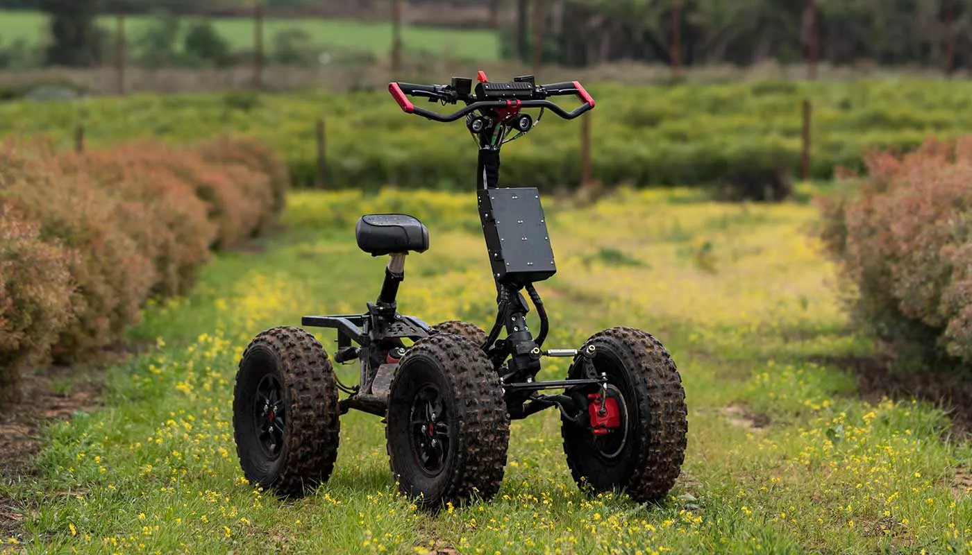 EZRaider HD4 4x4 off-road electric scooter with seat parked on grassy trail surrounded by green and brown bushes